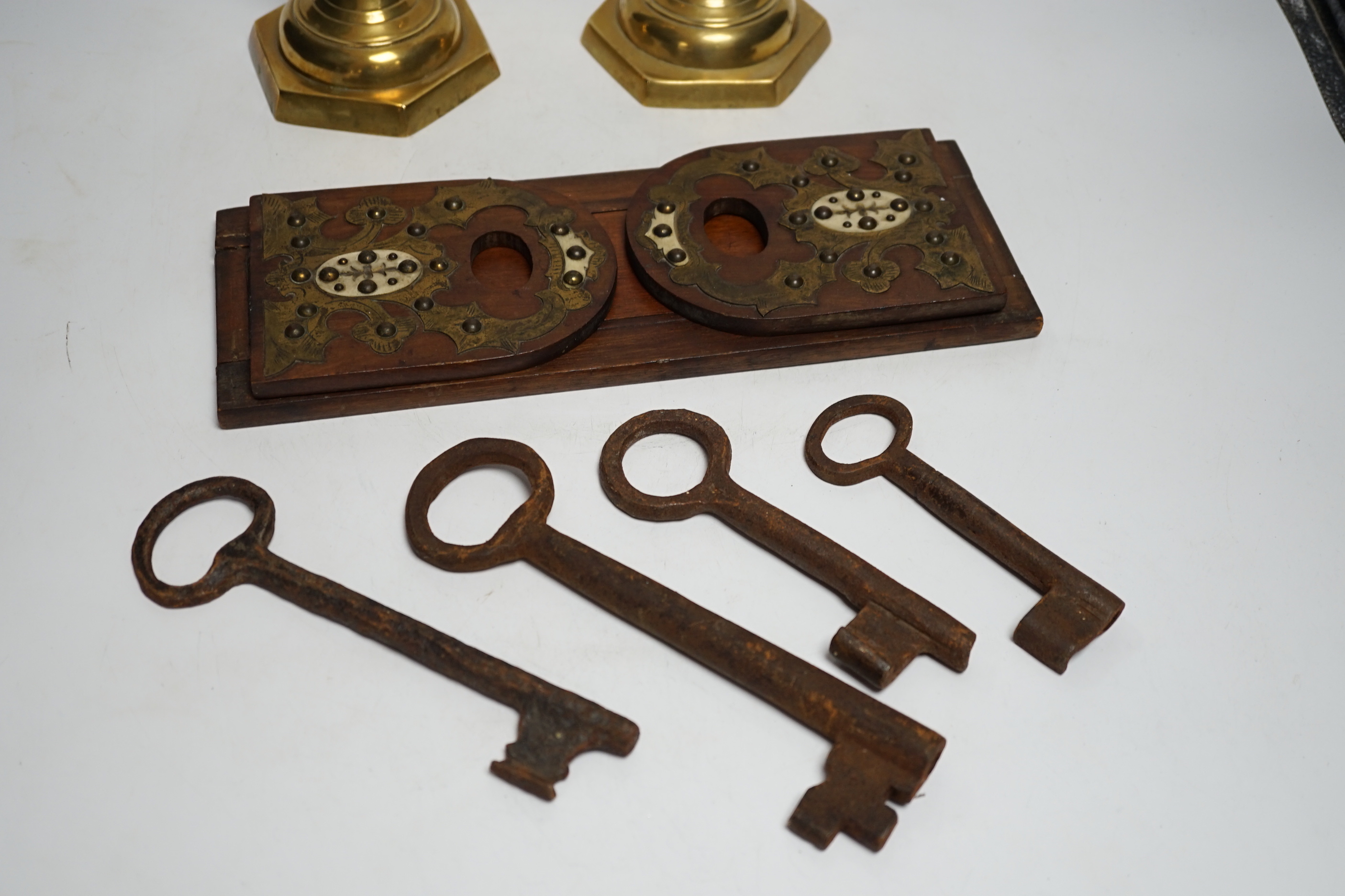 A group of mixed metalware including a pair of brass candlesticks, a brass bound book slide, iron keys, etc.